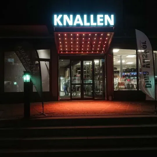 Upplyst fasadskylt i skymning